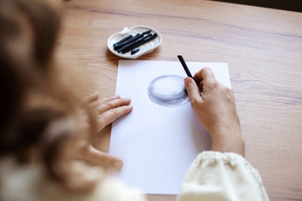 Artist Sketching Sphere with Charcoal on Paper